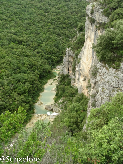 Une photo prise depuis le haut d'une falaise montrant les concluses de Lussan, des gorges creusées par l'eau dans la roche calcaire.