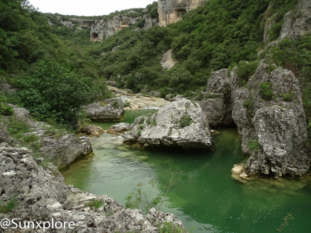 Une photo qui montre l'eau qui s'écoule lentement au coeur des concluses de Lussan, des formations rocheuses creusées par l'érosion dans le Gard.
