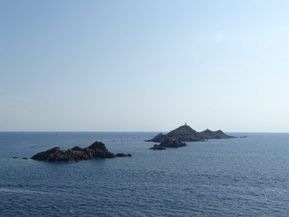 Une photo qui montre quatre îles rocheuses au large de la côte corse, surmontées par un ciel bleu