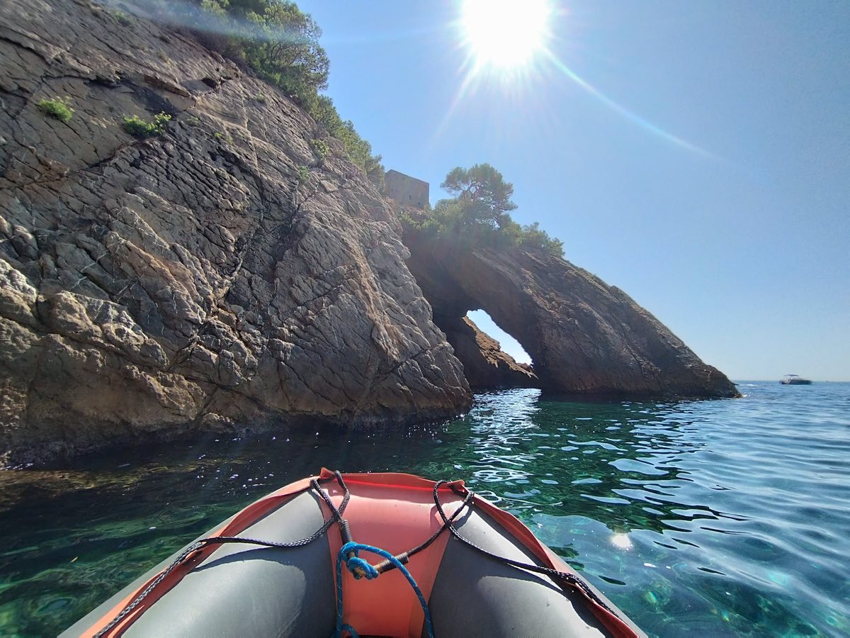 Arche naturelle de la calanque de la Madrague vue depuis un kayak, mer turquoise et falaises ocres