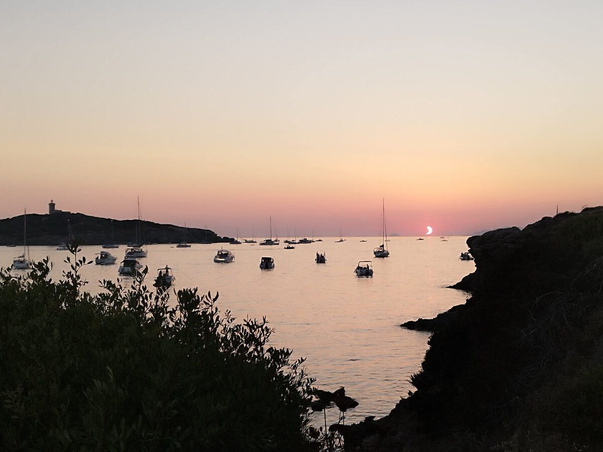 Bateaux au mouillage sous un ciel rose au crépuscule, avec le croissant de Soleil encore visible, île des Embiez
